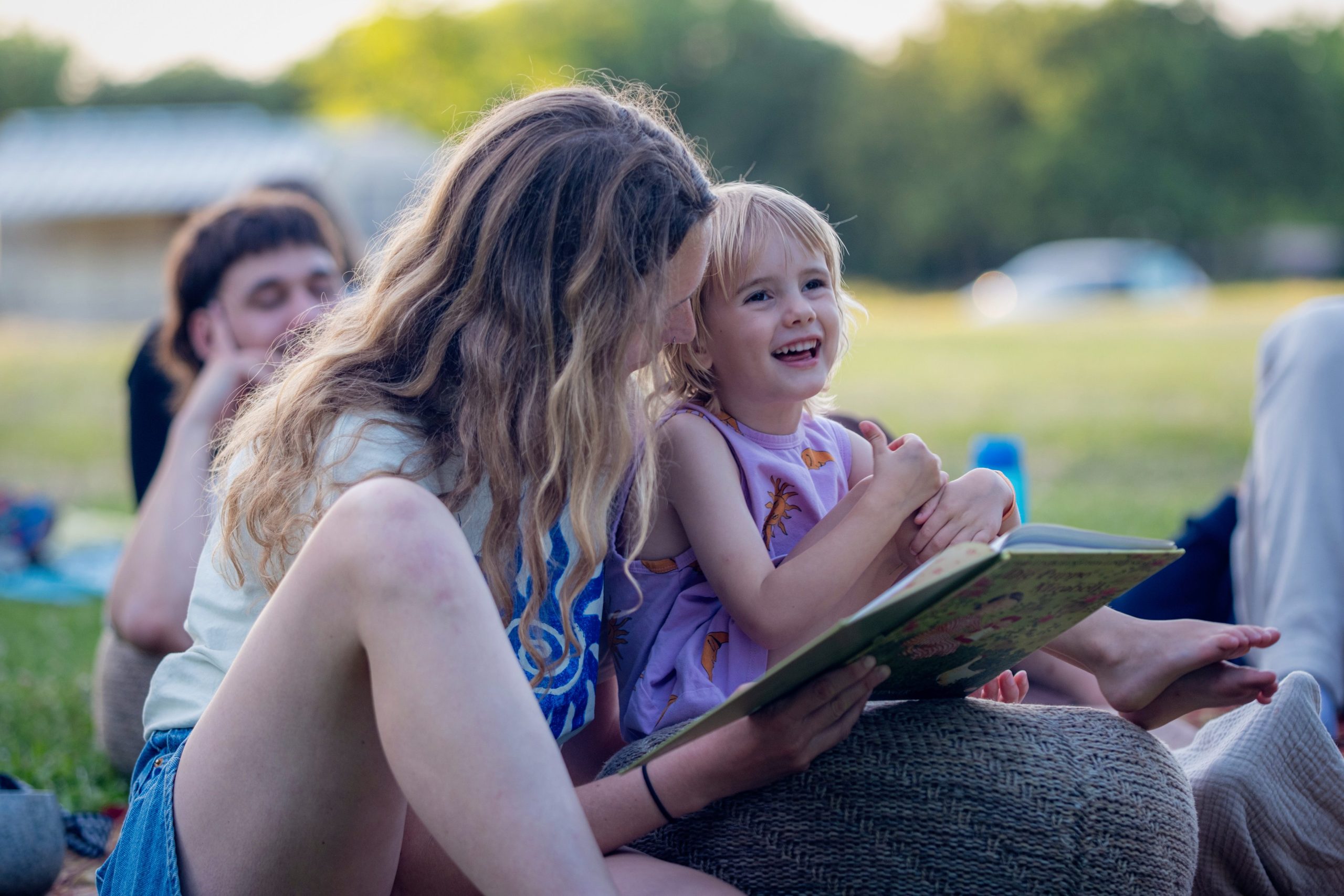 Innere Prägung: Frau und Kind beim Lesen Eine Frau hält ein lachendes Kind im Arm, vor ihnen liegt ein aufgeschlagenes Buch.